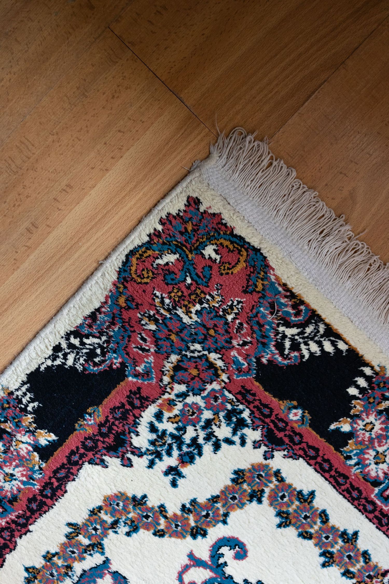 Coin d'un tapis d'Orient à bordure fleurie posé sur un parquet
